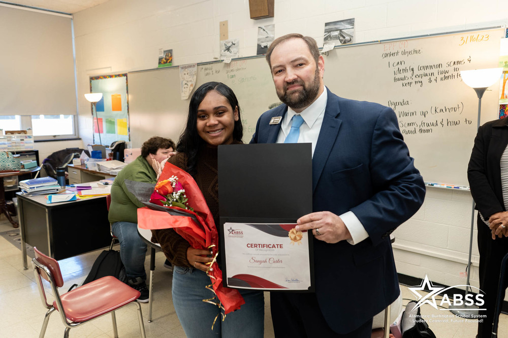 Dr. Butler with Graham High School Student holding certificate and flowers announcing Governor School selection 