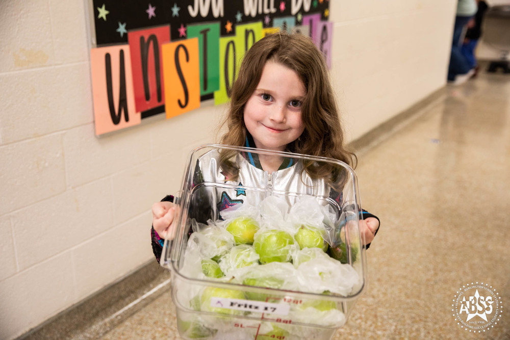 Grove Park Elementary student holding a bucket full of green apples.  