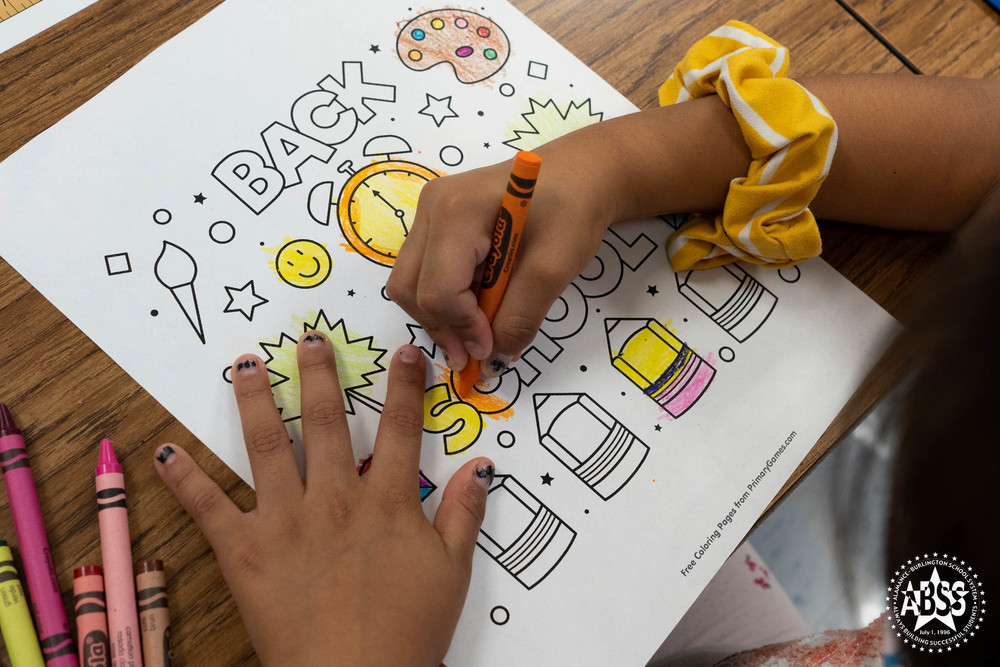 Photo of an elementary student coloring a Back to School paper