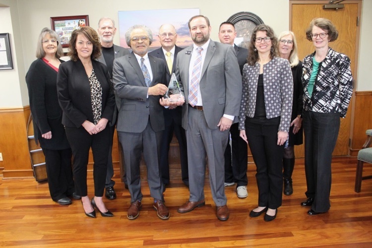 group photo of ABSS Board members & superintendent with leaders from ACC holding trophy.  