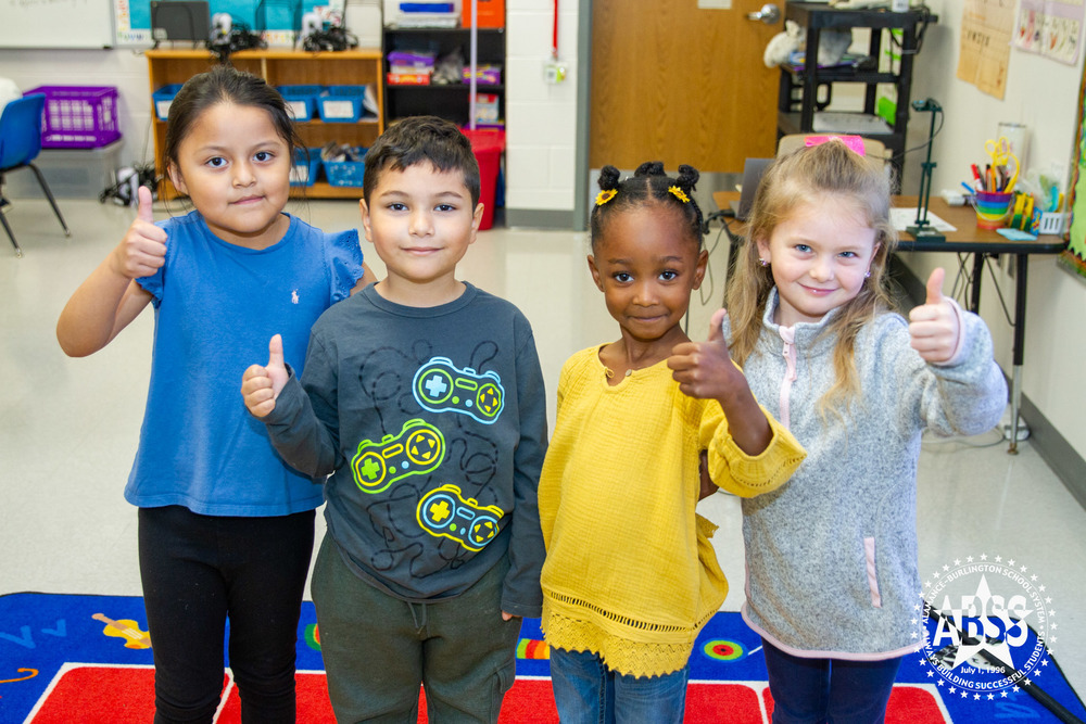 Four kindergarten students from Elon University giving a thumbs up in their classroom