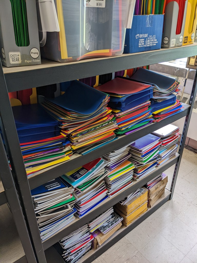 Three metal shelves stacked full of student folders of different colors