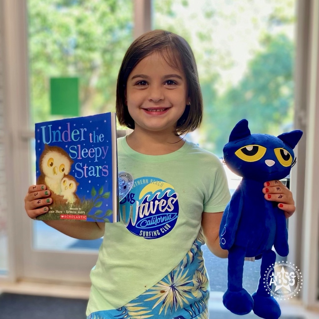 Kindergarten student holding a book in her right hand and Pete the Cat in her left hand