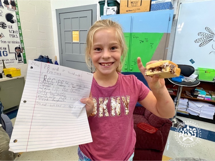 student holding recipe and homemade peanut butter sandwich