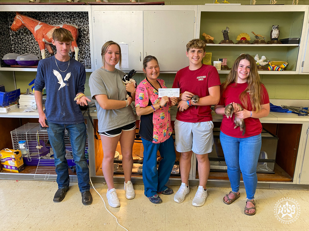 Southern Alamance High School animal science students holding animals beside staff member Tasha Dawson who is holding a check