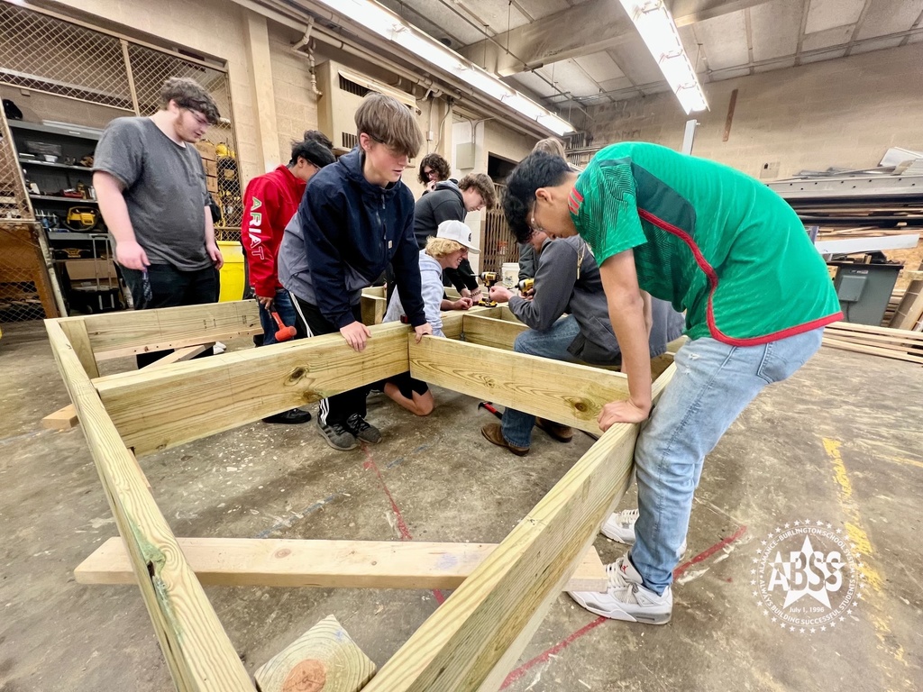 Carpentry students at Eastern Alamance High School working together to create a floor joist for a building foundation using wooden beams.