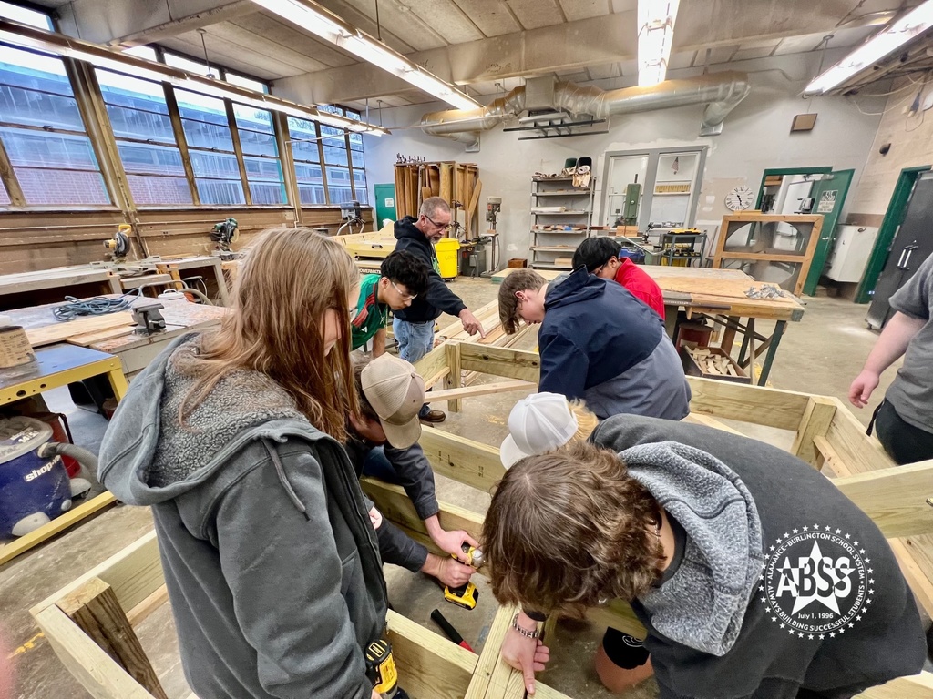 Carpentry students at Eastern Alamance High School working together to create a floor joist for a building foundation using wooden beams.  An instructor is pointing at one of the wooden beams.