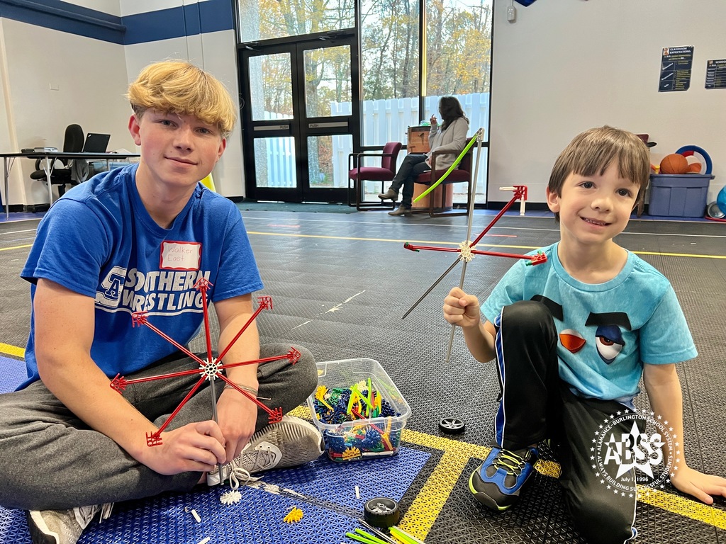 A member of the Southern Alamance High School Student Council and an elementary student show the ferris wheels they constructed using KNEX on the gym floor