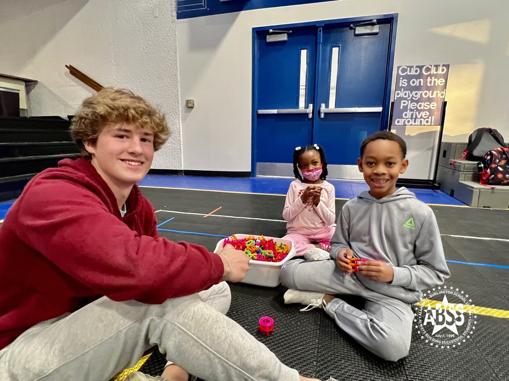 A member of the Southern Alamance High School Student Council and an elementary student build objects from connector blocks on the gym floor