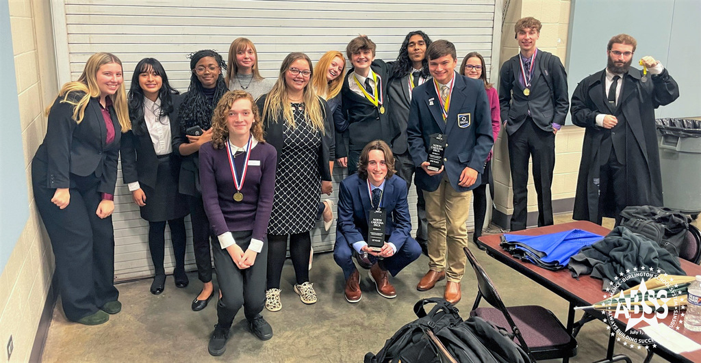 A group photograph of Eastern Alamance High School DECA marketing students at the District 4 DECA competition.  They are dressed formally and some are wearing medals or holding trophies in recognition of their marketing ideas.