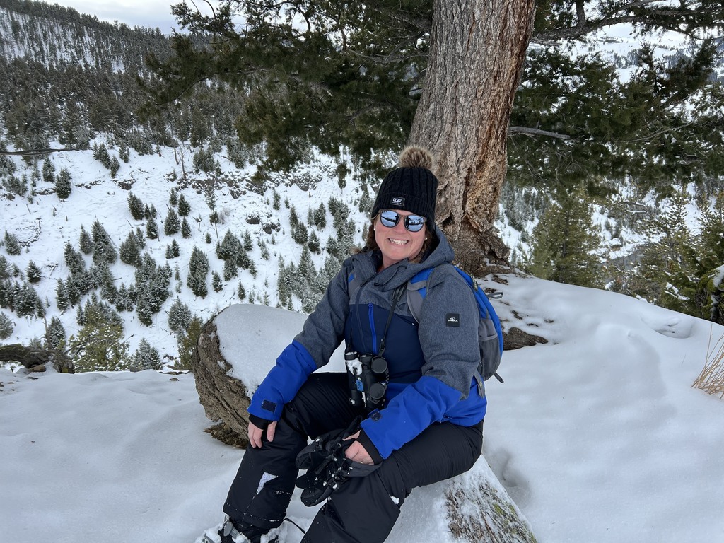 Alamance Virtual School teacher Tonya Dobson sitting on a snowy hill in winter gear at Yellowstone National Park