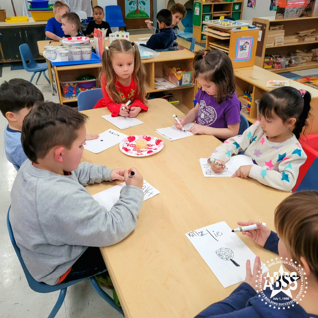 Six pre-kindergarten students sit around a table and draw their observation of a frozen snack melting on a paper plate