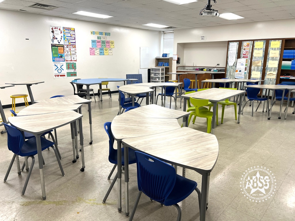 A classroom at Broadview Middle School with new student desks and chairs.  The desks are arranged in groups of three with one additional table in the front middle.