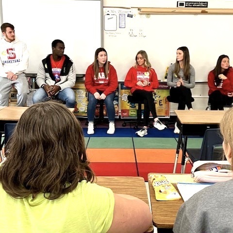 Southern high school students talking with students at Alexander Wilson AP about making good choices. Group of high school students sitting in front of elementary school students 