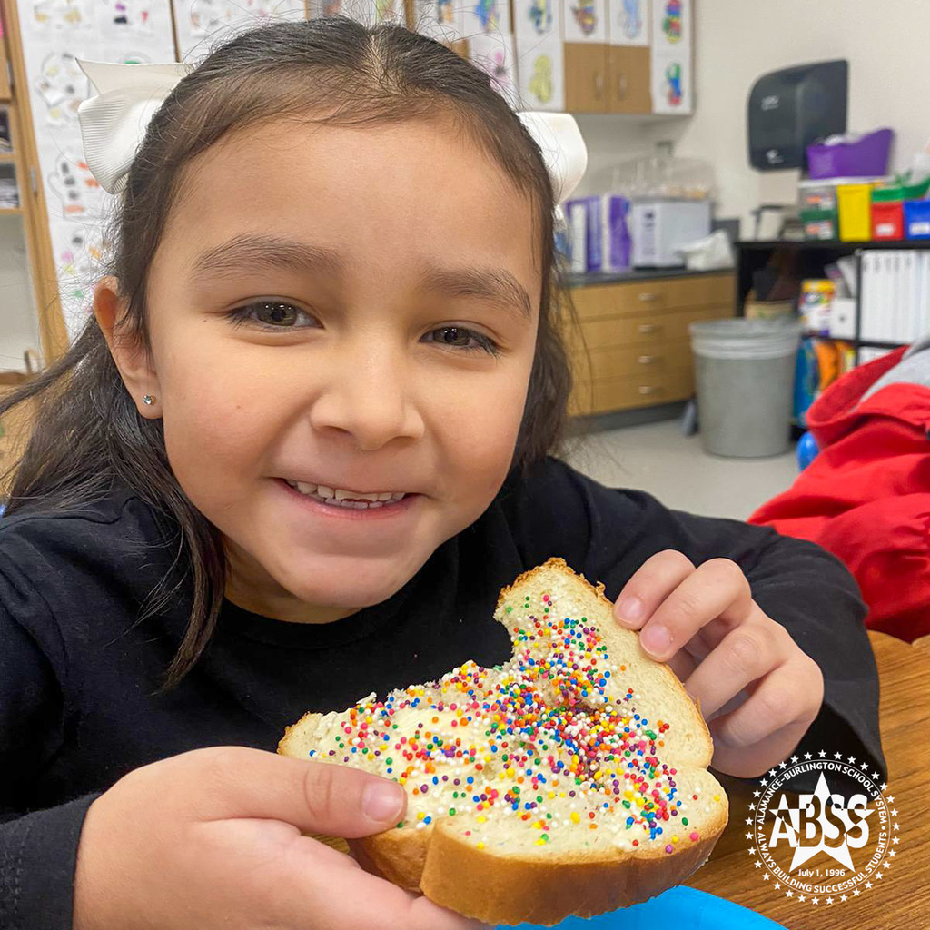 A kindergarten student smiles at the camera while eating fairy bread as part of the Australia Day activities