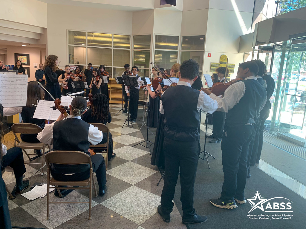 The Williams High School orchestra dressed in black and white plays in the lobby of the North Carolina Department of Public Instruction building in Raleigh