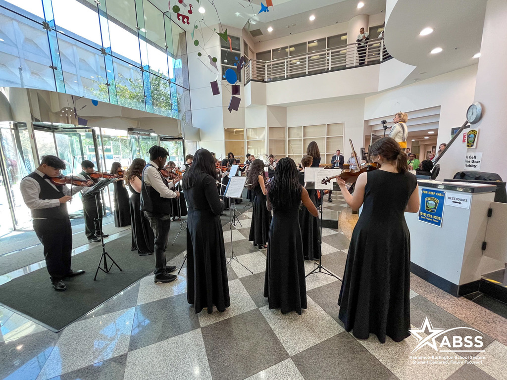 The Williams High School orchestra dressed in black and white plays in the lobby of the North Carolina Department of Public Instruction building in Raleigh