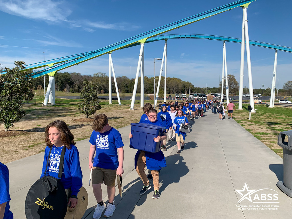 The Western Alamance Middle School 7th & 8th Grade Band walking on a cement path under a rollercoaster at Carowinds