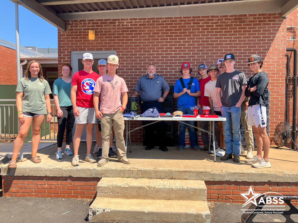 Southern Alamance High School students and a local officer standing with a table of supplies as part of the Prom Promise event