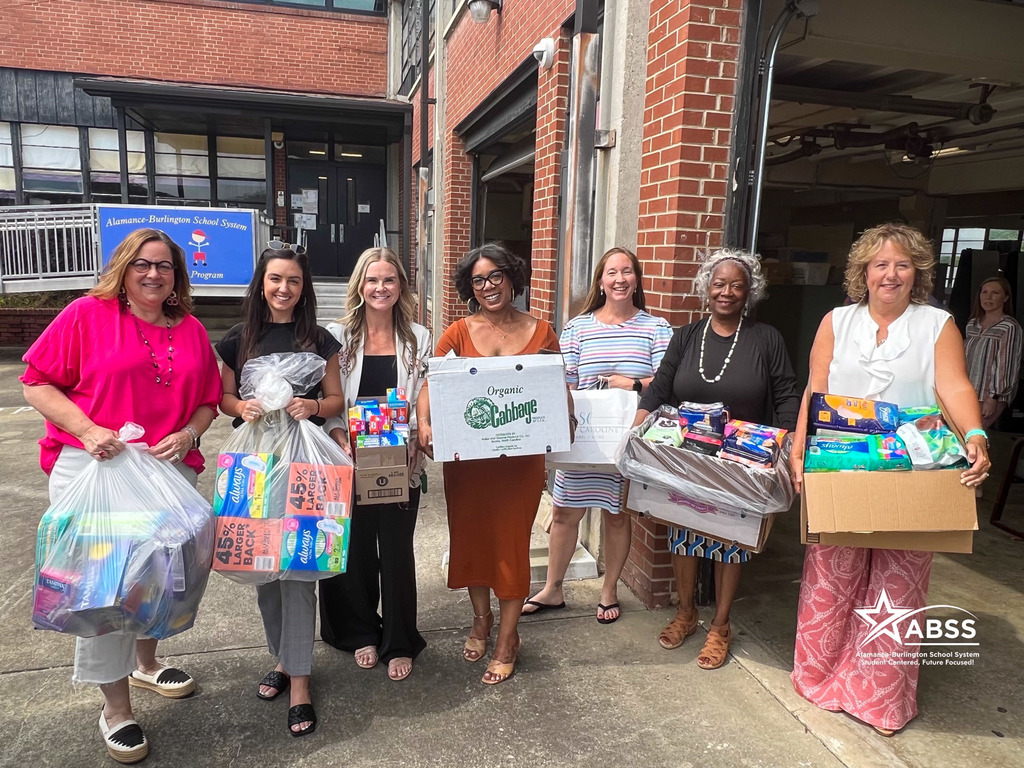 Members of the ROAR Women's Symposium and the Alamance Chamber hold donated feminine hygiene products