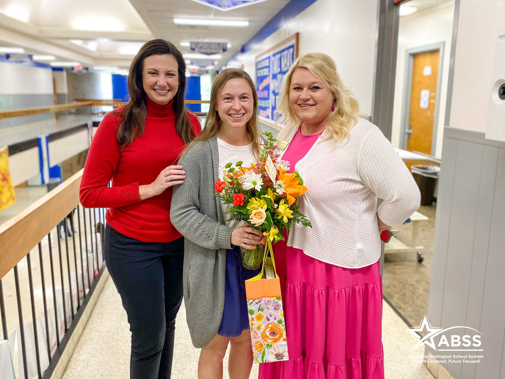 ABSS Counselor of the Year Anne Goldberg accepting flowers and a plaque in the hallway of Broadview Middle