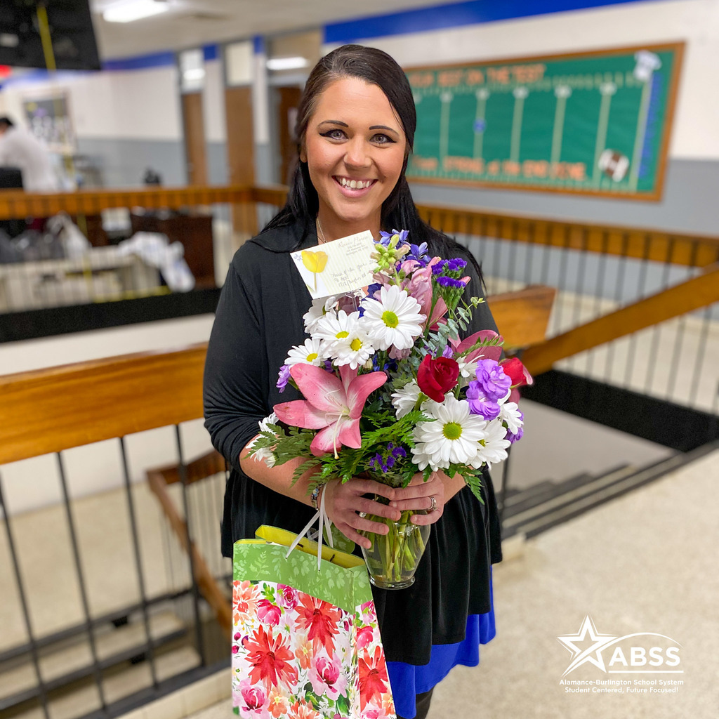 School Nurse of the Year Rebecca Hudson standing with flowers and a gift bag at Broadview Middle School