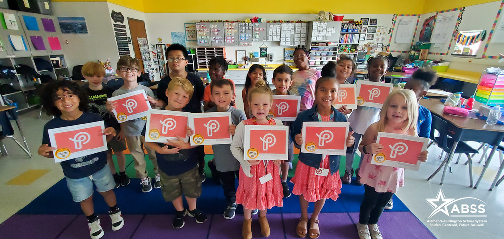Class photograph of first graders holding their published book about an educational game called Prodigy