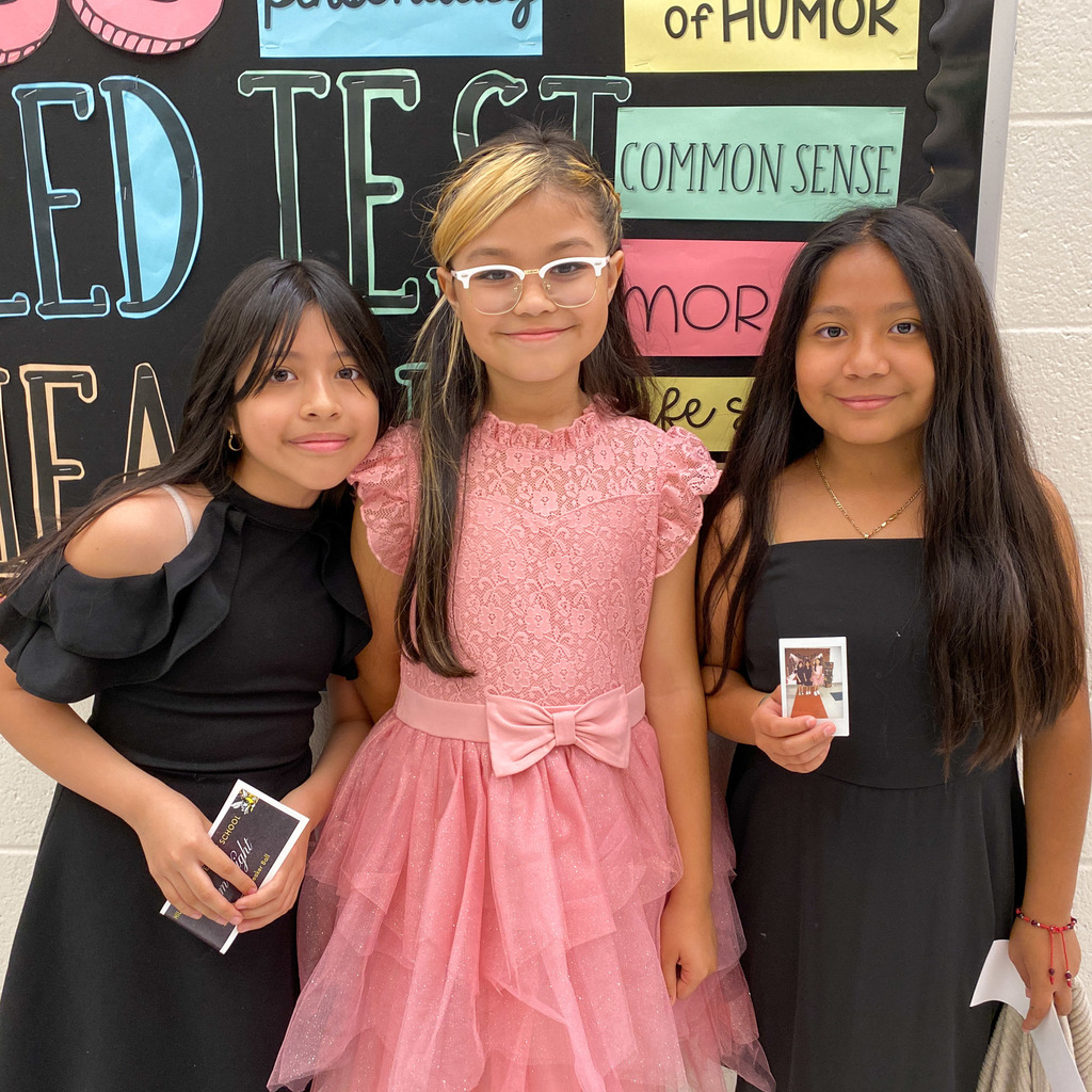 Three girls from Hillcrest Elementary wearing dresses and one is holding a film photograph they took at the photo booth as part of the Sneaker Ball event