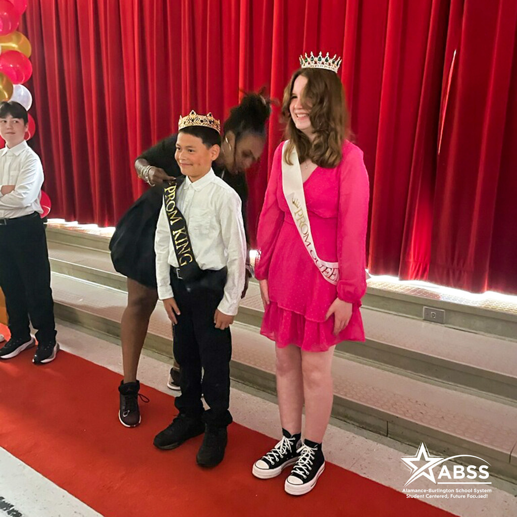 Two students crowned King and Queen  of the Sneaker Ball at Hillcrest Elementary standing on red carpet in front of red curtain