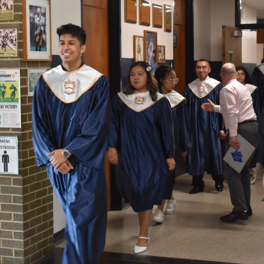 Students at Cummings High School walking in line in their gowns towards the Capping Ceremony