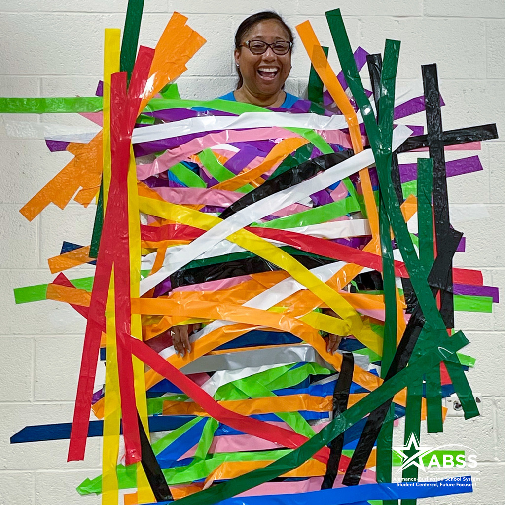 Principal Traci Horton laughs while taped to a wall with tape of various colors