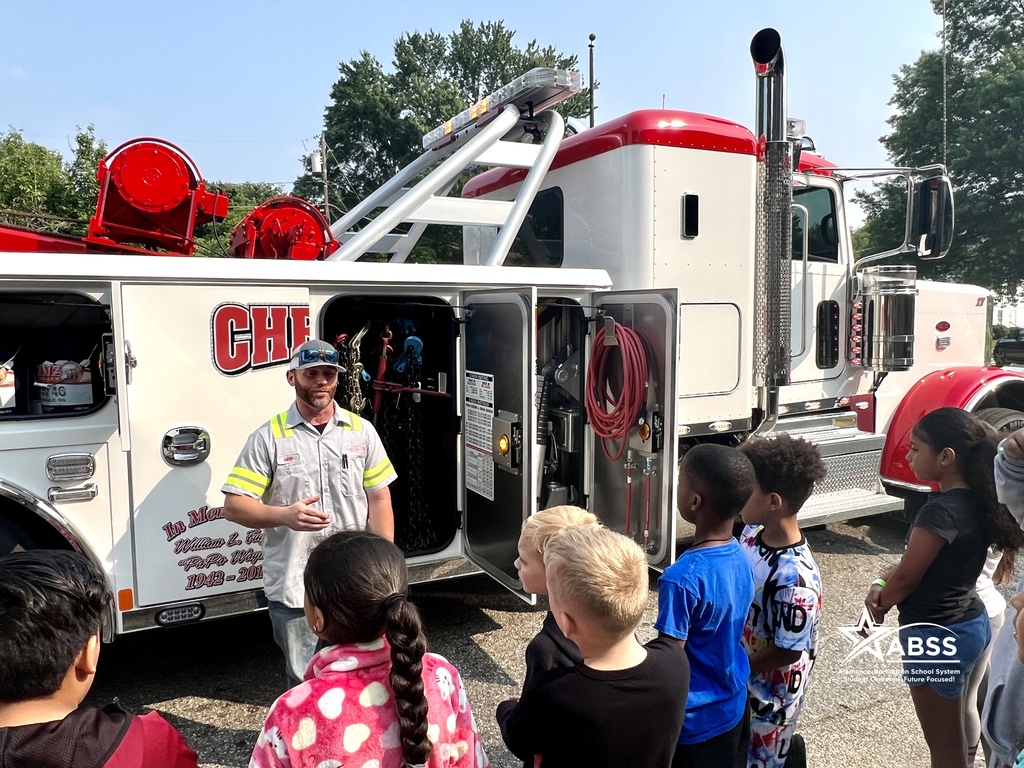 Students at Newlin Elementary listen to a Burlington Firefighter talk about his job in front of a fire truck 