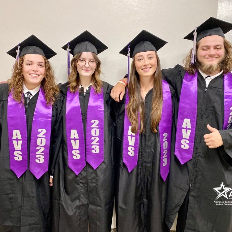 Four seniors from Alamance Virtual School standing together in black and purple robes