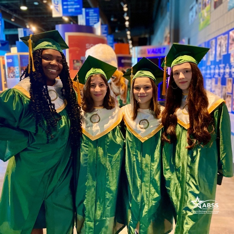 Four graduates of Eastern Alamance High School in robes posing for a photograph 