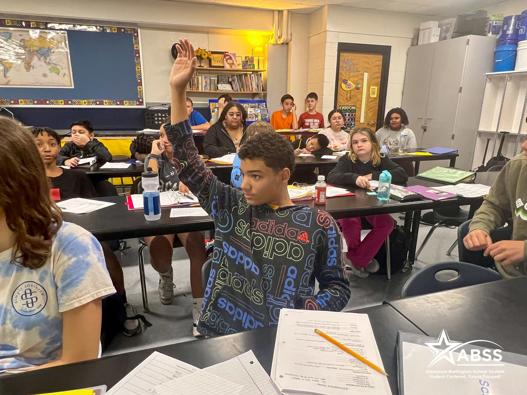 A student raises his hand with focus on the teacher at Southern Middle School
