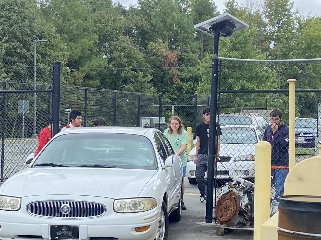 High school students work together to move a car