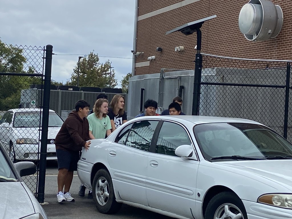 High school students work together to move a car