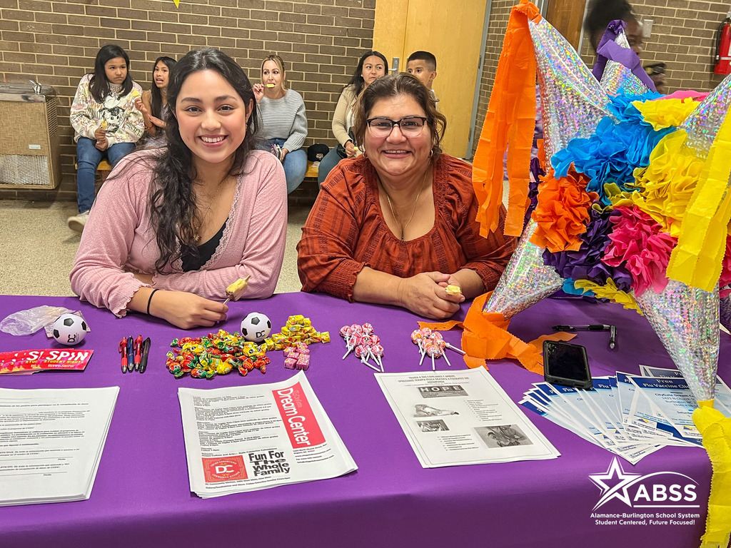 Two representatives from the Citygate Dream Center smile behind a table with purple tablecloth, cultural decorations, and information