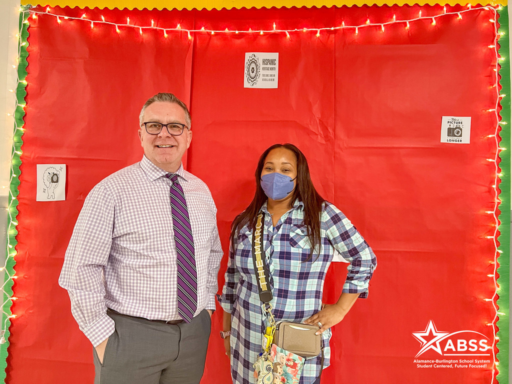Public Information Officer Les Atkins poses with Assistant Principal JaTara McIntyre in front of a red backdrop and lights