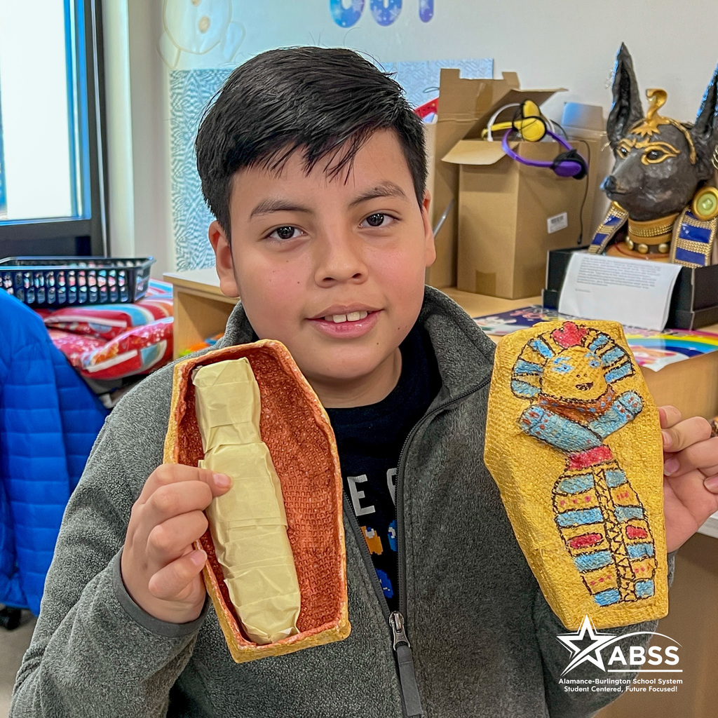 A Broadview Middle School student holds up a model sarcophagus and mummy