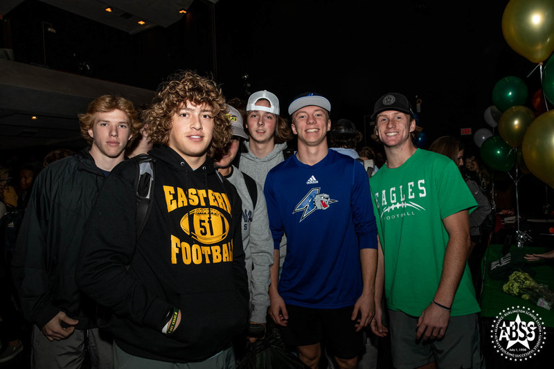 Cole McGinnis signed with UNC Asheville. Image of Cole with other student athletes congratulating him following his signing  