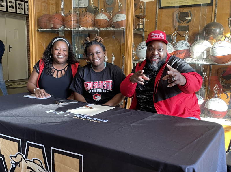 Walter Williams High School softball standout Jai'Nasia Bailey seated at table with her family.  All wearing Winston Salem State college gear