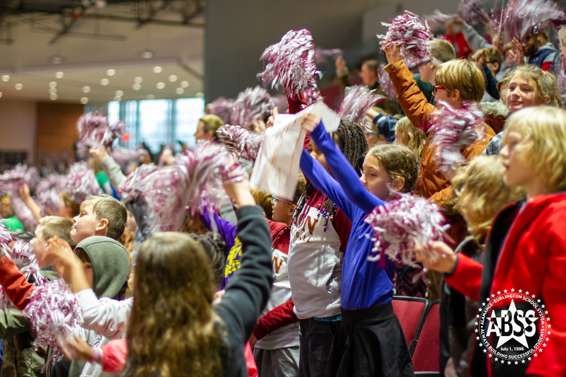 A side angle shot of students cheering with pompons at a women's basketball game at Elon University