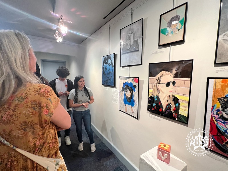 People viewing artwork at student explains her inspiration 