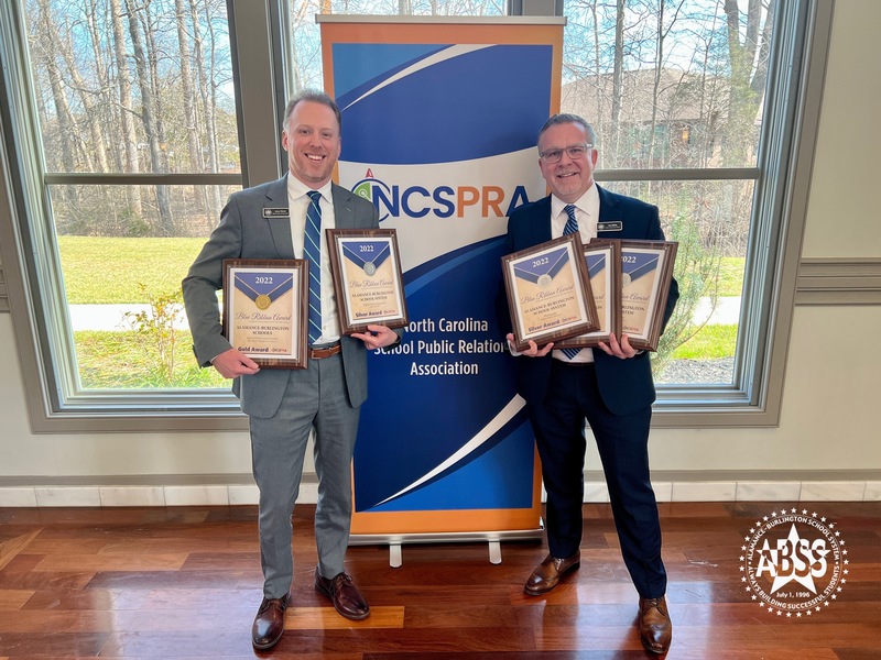 ABSS Public Information Officer Les Atkins and Digital Media Coordinator James Shuler holding plaques in front of NCSPRA banner at awards ceremony in High Point, NC 