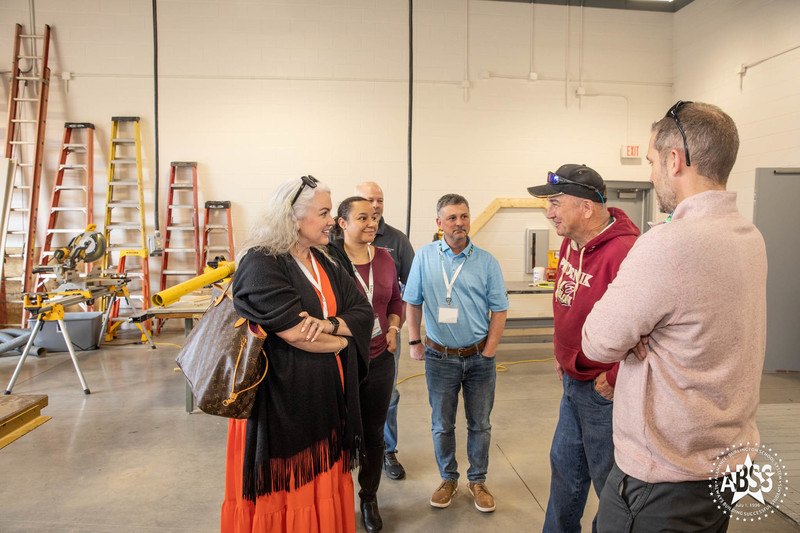 Carpentry instructor at Southern High School telling Leadership Alamance group about his program.  Ladders and other carpentry machinery in background.  