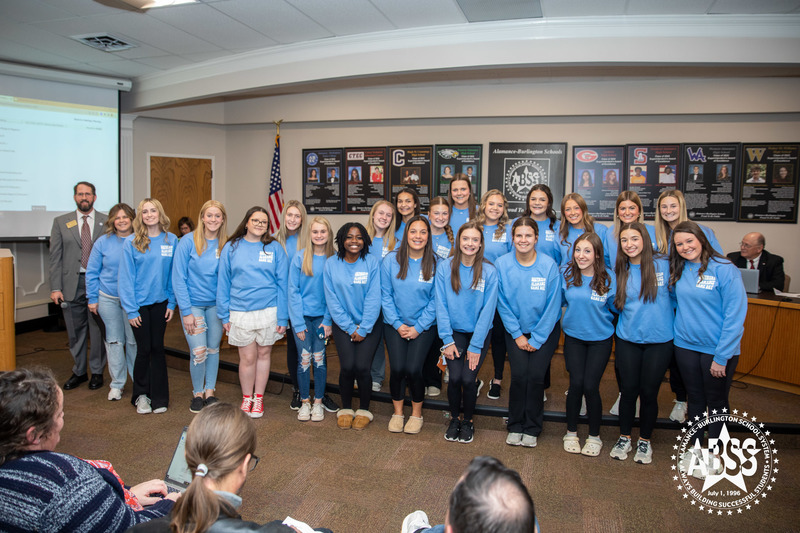 Group photograph of the Southern Alamance High School cheer team standing in front of the Board of Education in blue long sleeve shirts.