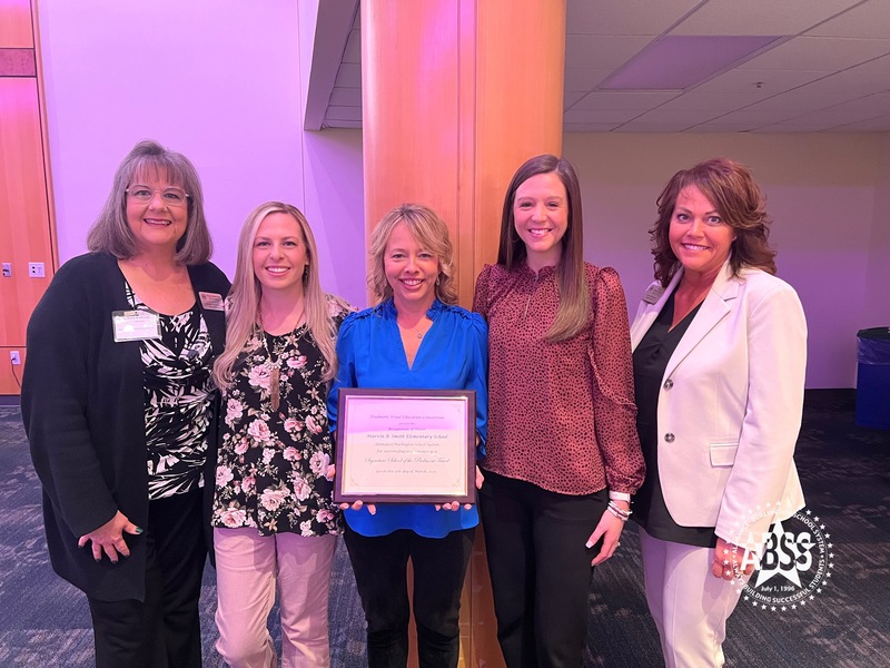 Smith Elementary team holding plaque posing for photo with Board of Education Chair Sandy Ellington-Graves and Board Member Donna Westbrooks