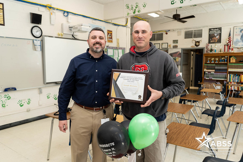 CTE Teacher of Year holding plaque posing with Principal Bear Bryant