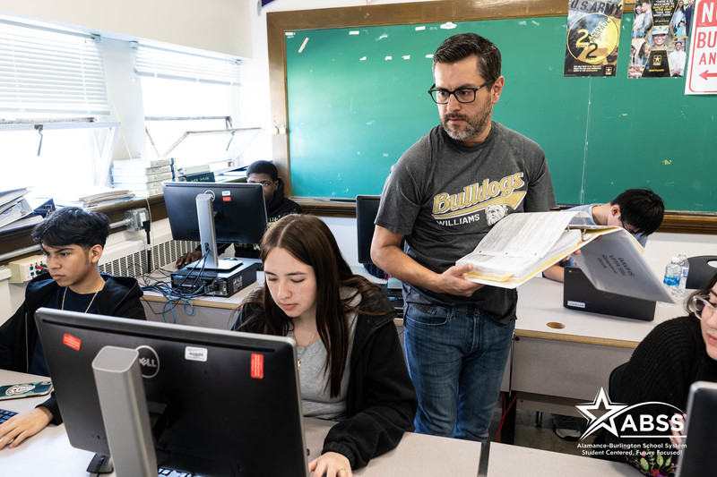 Accounting instructor helping students in a computer lab at Williams High